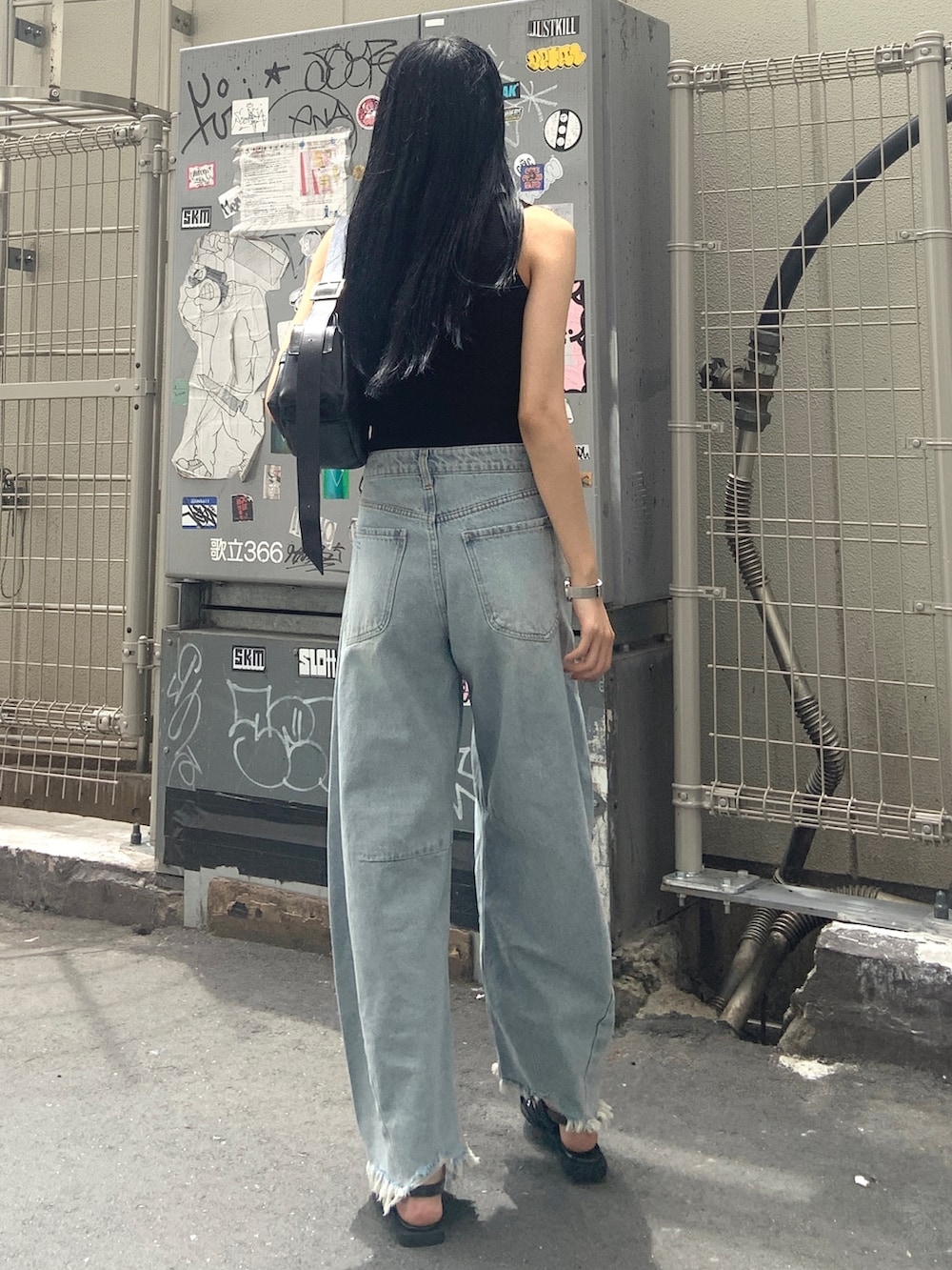 ブラック系のニット/セーター、ブルー系のデニムパンツ、ブラック系のパンプスを着用したレディースの夏コーディネートの3枚目の写真