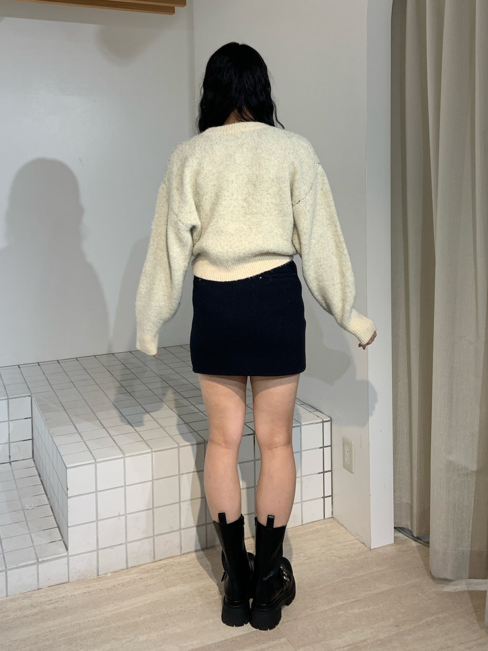 ホワイト系のニット/セーター、ブルー系のスカート、ブラック系のブーツを着用したレディースの秋コーディネートの3枚目の写真