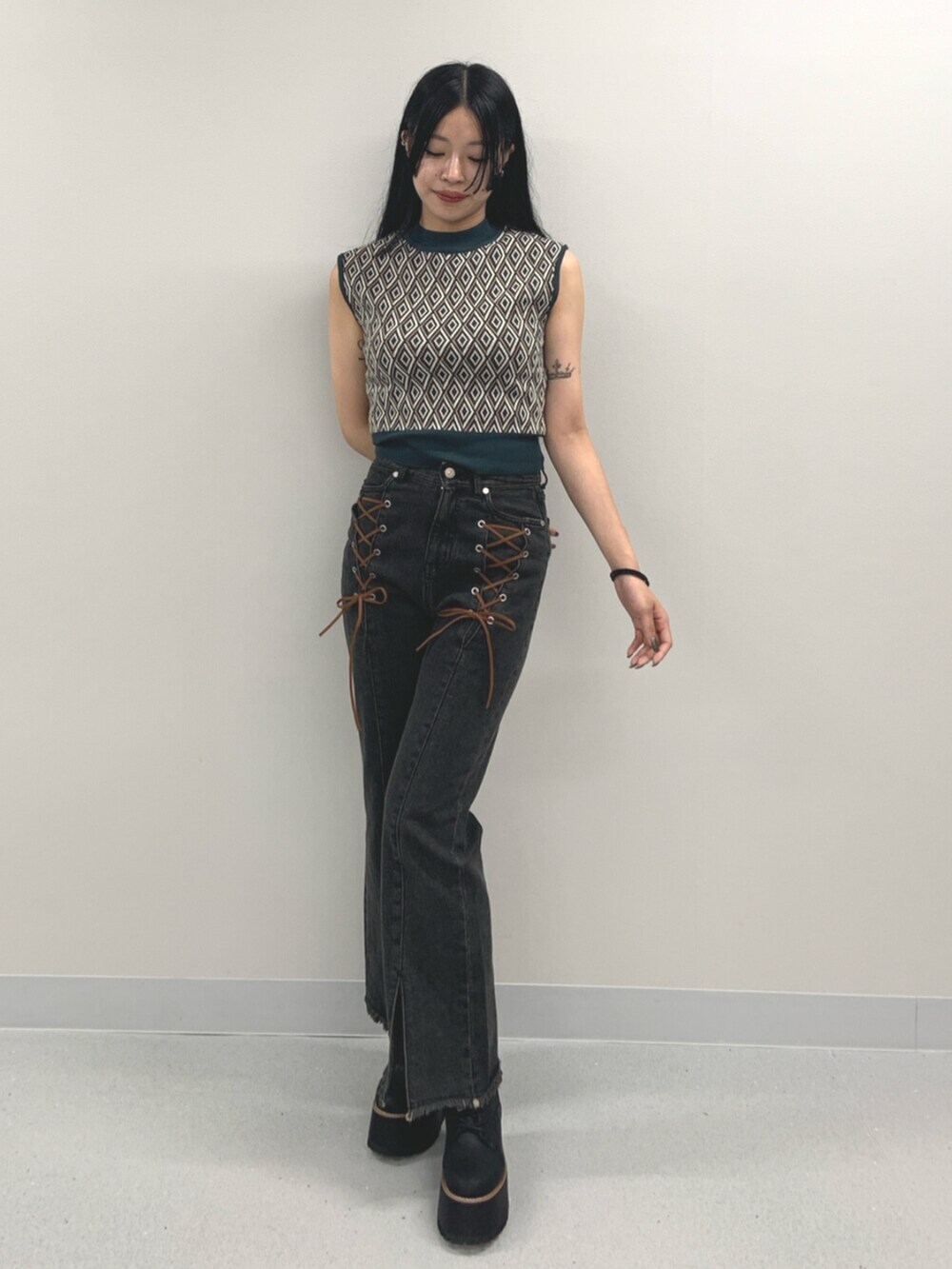 ブラック系のデニムパンツ、ブラック系のブーツ、グリーン系のタンクトップを着用したレディースの夏コーディネートの2枚目の写真