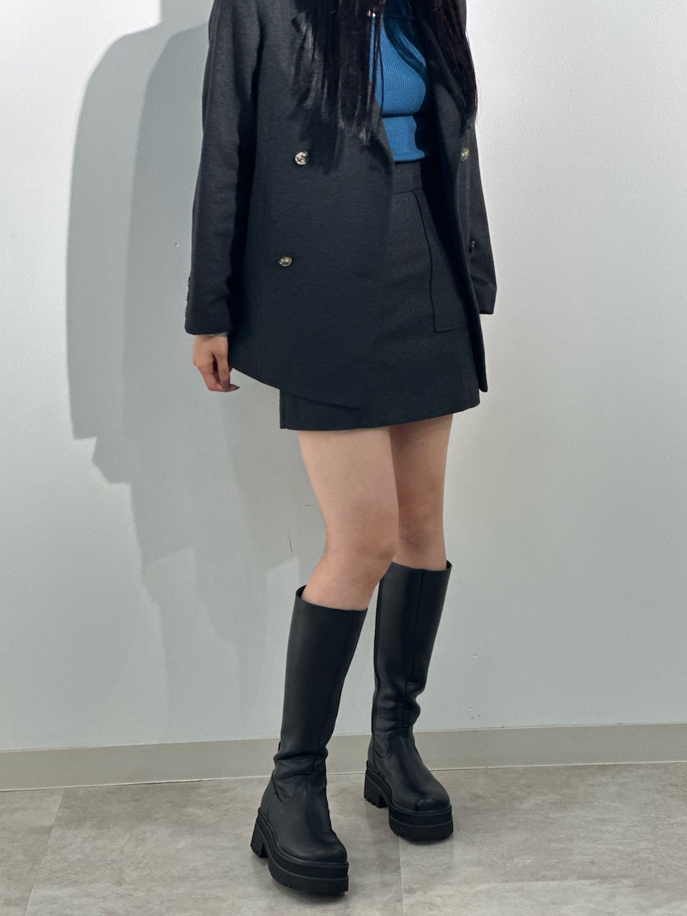 グレー系のテーラードジャケット、ブルー系のニット/セーター、グレー系のスカートを着用したレディースの秋コーディネートの2枚目の写真