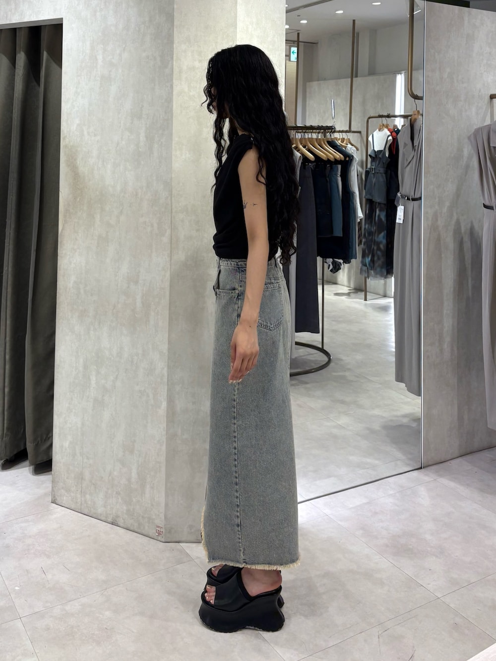 ブラック系のTシャツ/カットソー、ブルー系のデニムスカート、ブラック系のサンダルを着用したレディースの夏コーディネートの2枚目の写真