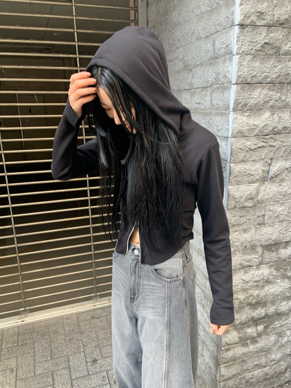 ブラック系のパーカー、ブラック系のデニムパンツ、ブラック系のブーツを着用したレディースの冬コーディネートの6枚目の写真