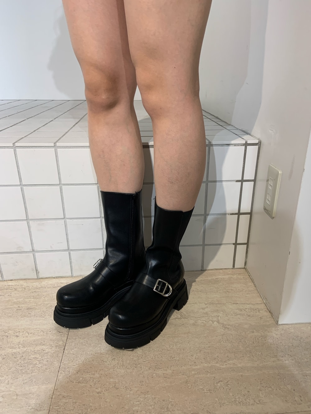 ホワイト系のニット/セーター、ブルー系のスカート、ブラック系のブーツを着用したレディースの秋コーディネートの5枚目の写真