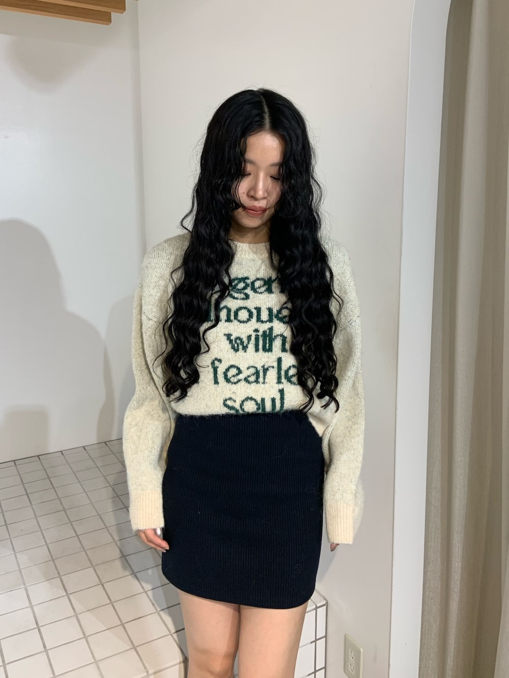 ホワイト系のニット/セーター、ブルー系のスカート、ブラック系のブーツを着用したレディースの秋コーディネートの4枚目の写真