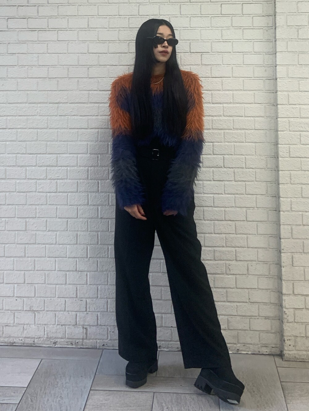 オレンジ系のニット/セーター、ブラック系のその他パンツ、ブラック系のブーツを着用したレディースの秋コーディネートの4枚目の写真