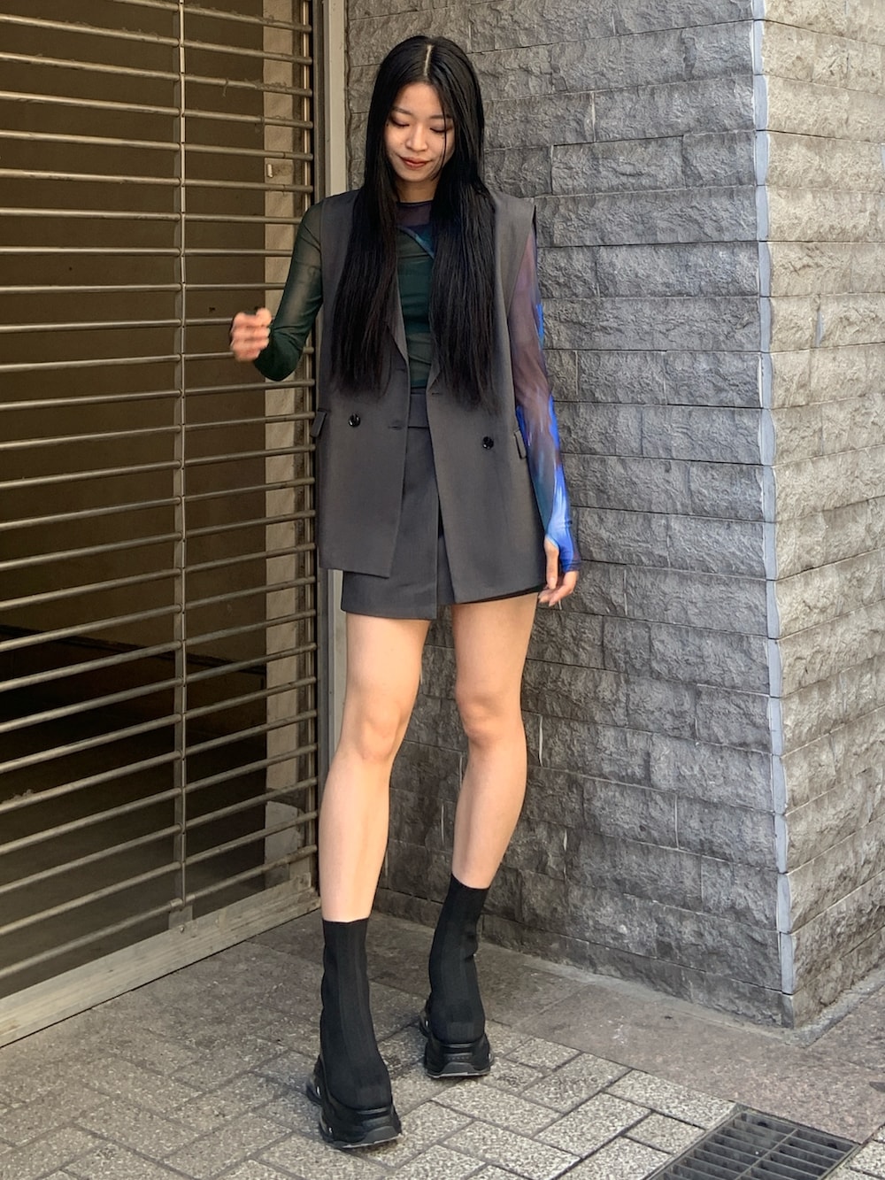 グレー系のベスト、グリーン系のTシャツ/カットソー、グレー系のスカートを着用したレディースの春コーディネートの2枚目の写真