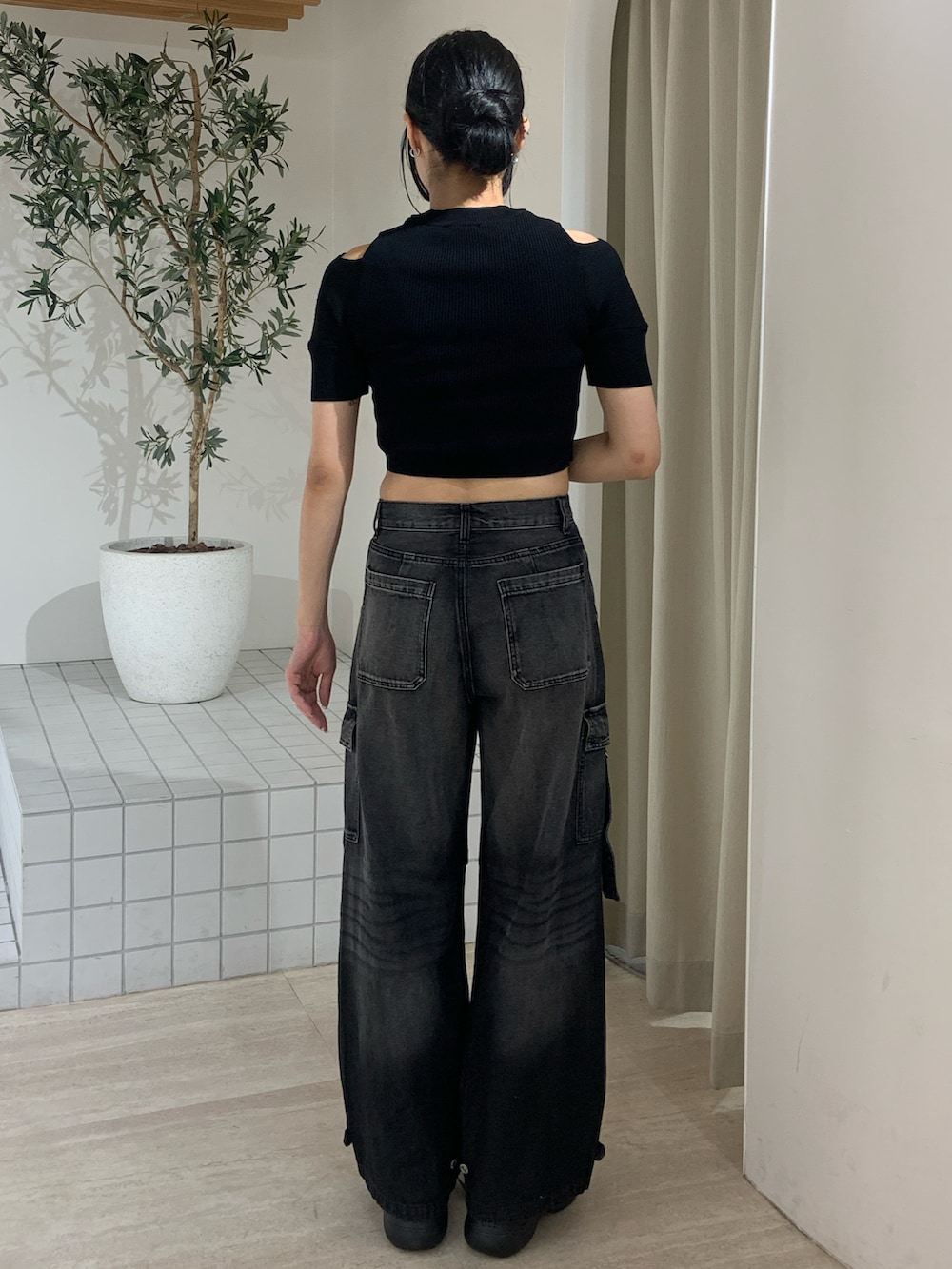 ブラック系のニット/セーター、ブラック系のデニムパンツ、ブラック系のサンダルを着用したレディースの夏コーディネートの4枚目の写真