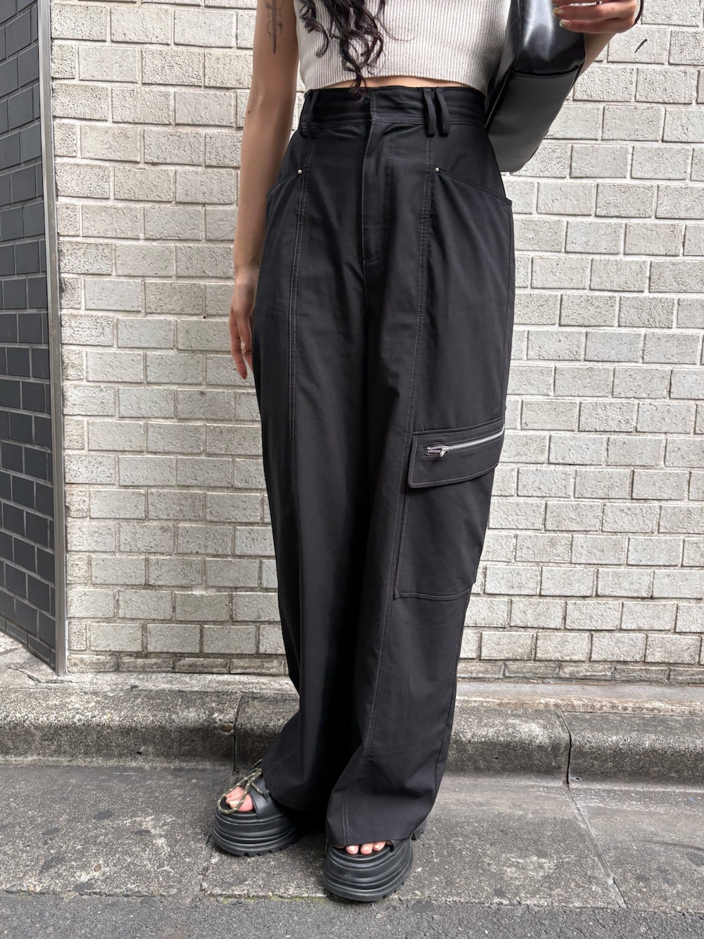 ホワイト系のニット/セーター、ブラック系のショルダーバッグ、ブラック系のスラックスを着用したレディースの夏コーディネートの6枚目の写真