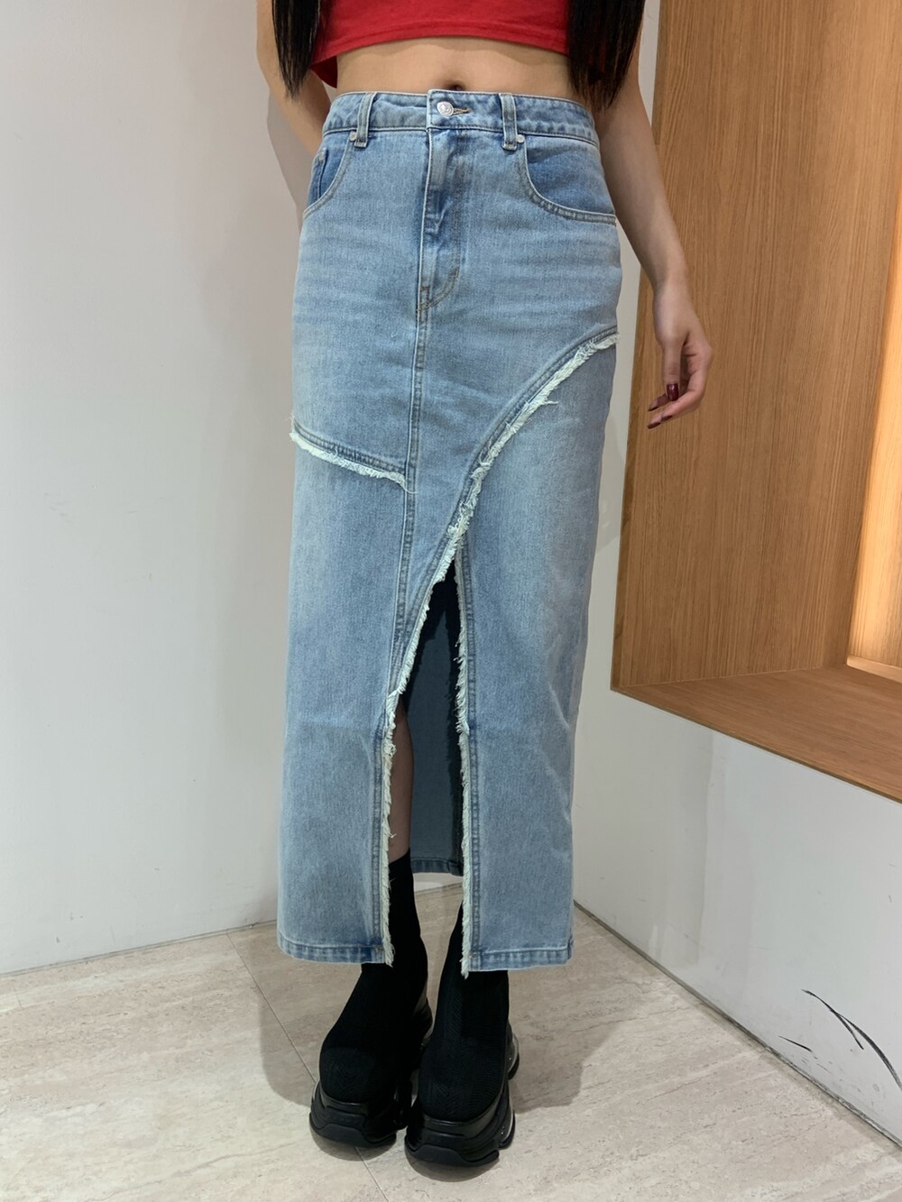 レッド系のTシャツ/カットソー、ブルー系のデニムスカート、ブラック系のブーツを着用したレディースの春コーディネートの6枚目の写真