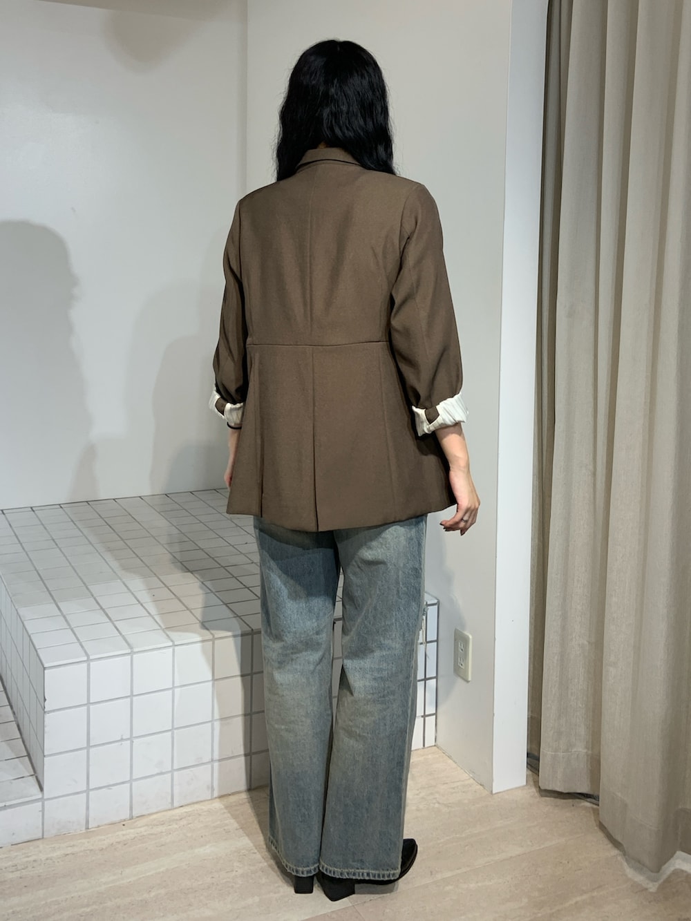 ブラウン系のブーツ、ブルー系のデニムパンツ、ブラウン系のテーラードジャケットを着用したレディースの秋コーディネートの3枚目の写真