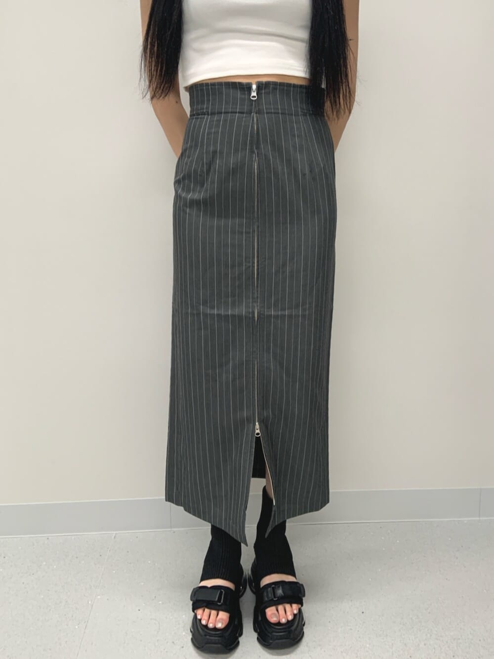 ブラック系のサンダル、ホワイト系のTシャツ/カットソー、グレー系のスカートを着用したレディースの春コーディネートの7枚目の写真
