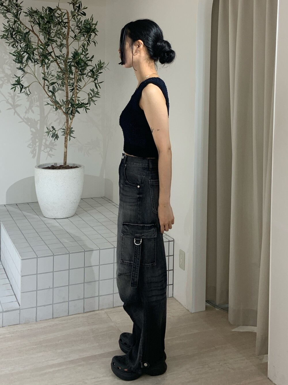 ブラック系のニット/セーター、ブラック系のデニムパンツ、ブラック系のサンダルを着用したレディースの夏コーディネートの3枚目の写真