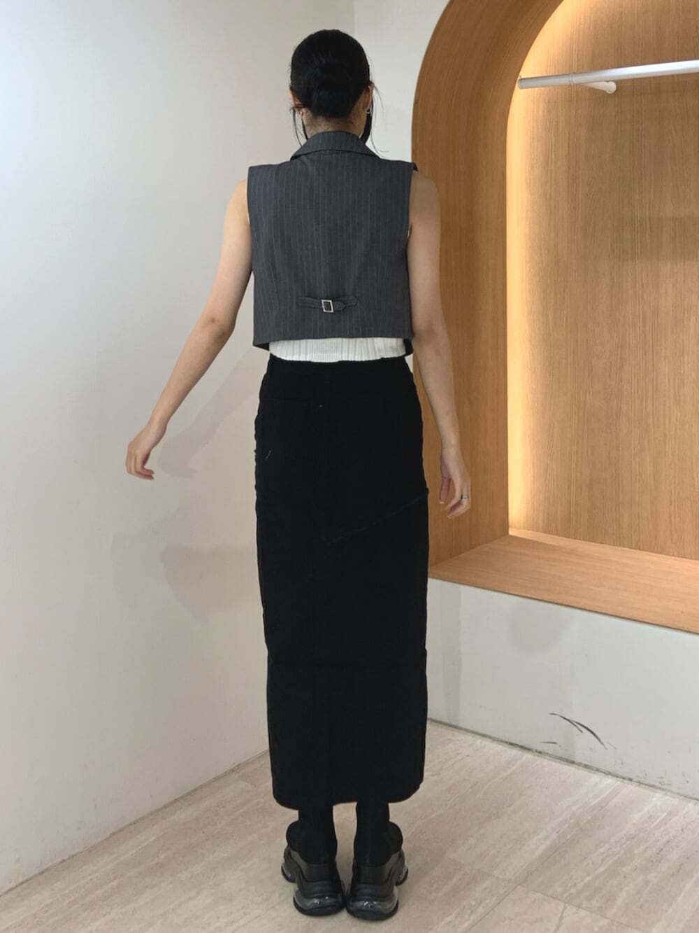 グレー系のベスト、ブラック系のサンダル、ブラック系のデニムスカートを着用したレディースの夏コーディネートの3枚目の写真