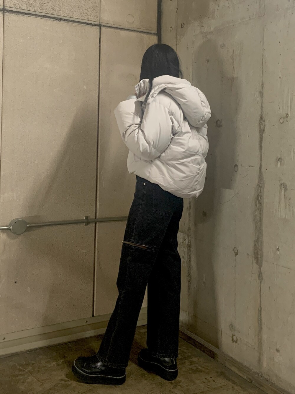 グレー系のダウンジャケット/コート、ブルー系のニット/セーター、ブラック系のデニムパンツを着用したレディースの秋コーディネートの3枚目の写真