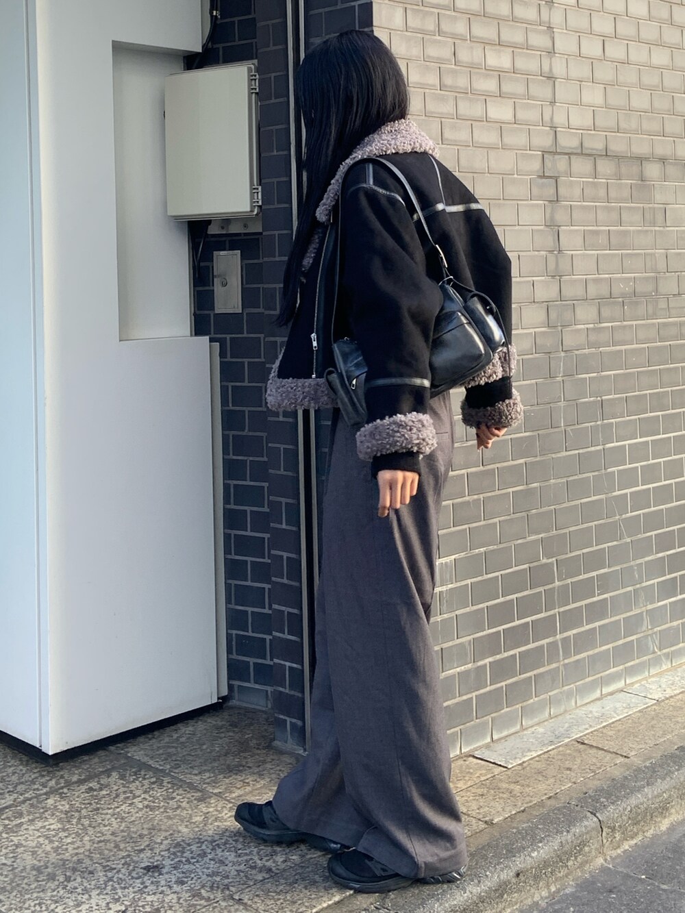 ブラック系のニット/セーター、グレー系のその他パンツ、ブラック系のムートンコートを着用したレディースの冬コーディネートの3枚目の写真