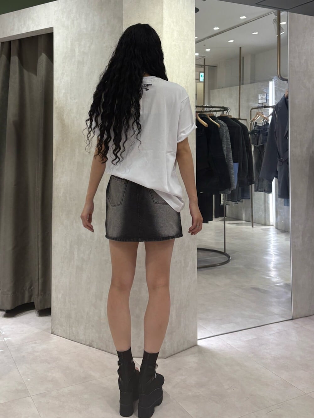 ブラック系のブーツ、ブラック系のデニムスカート、ホワイト系のTシャツ/カットソーを着用したレディースの春コーディネートの3枚目の写真