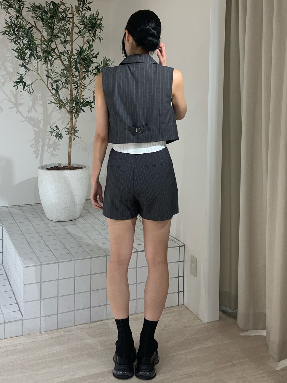 グレー系のベスト、ブラック系のサンダル、ホワイト系のタンクトップを着用したレディースの夏コーディネートの4枚目の写真