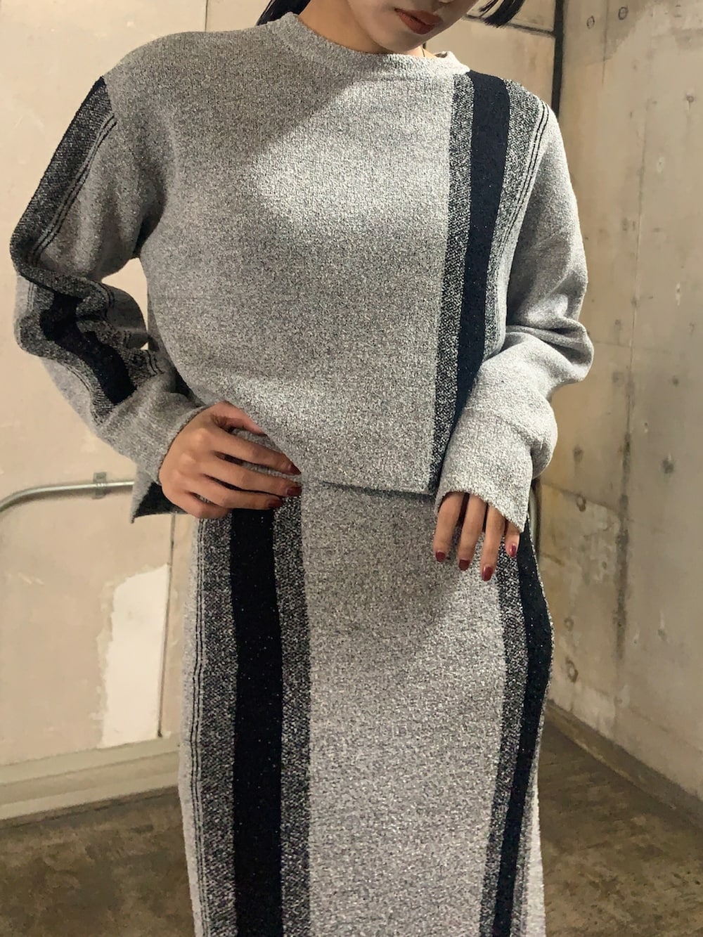 グレー系のニット/セーター、グレー系のスカート、ブラック系のブーツを着用したレディースの冬コーディネートの3枚目の写真