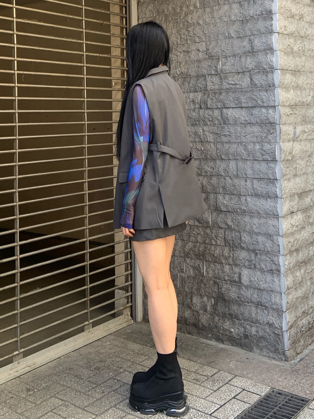 グレー系のベスト、グリーン系のTシャツ/カットソー、グレー系のスカートを着用したレディースの春コーディネートの3枚目の写真