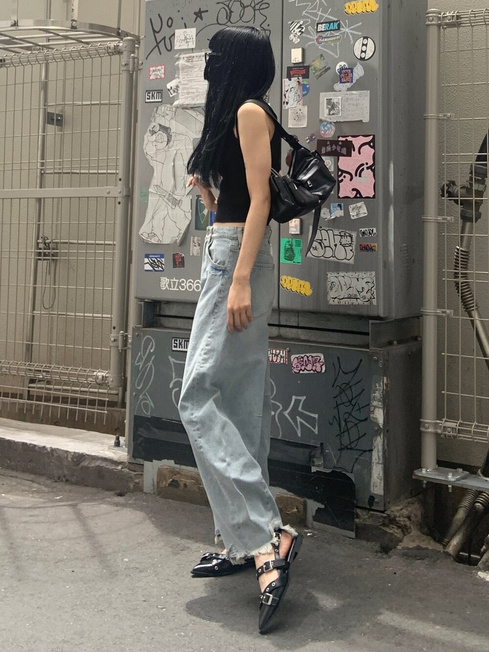 ブラック系のニット/セーター、ブルー系のデニムパンツ、ブラック系のパンプスを着用したレディースの夏コーディネートの2枚目の写真