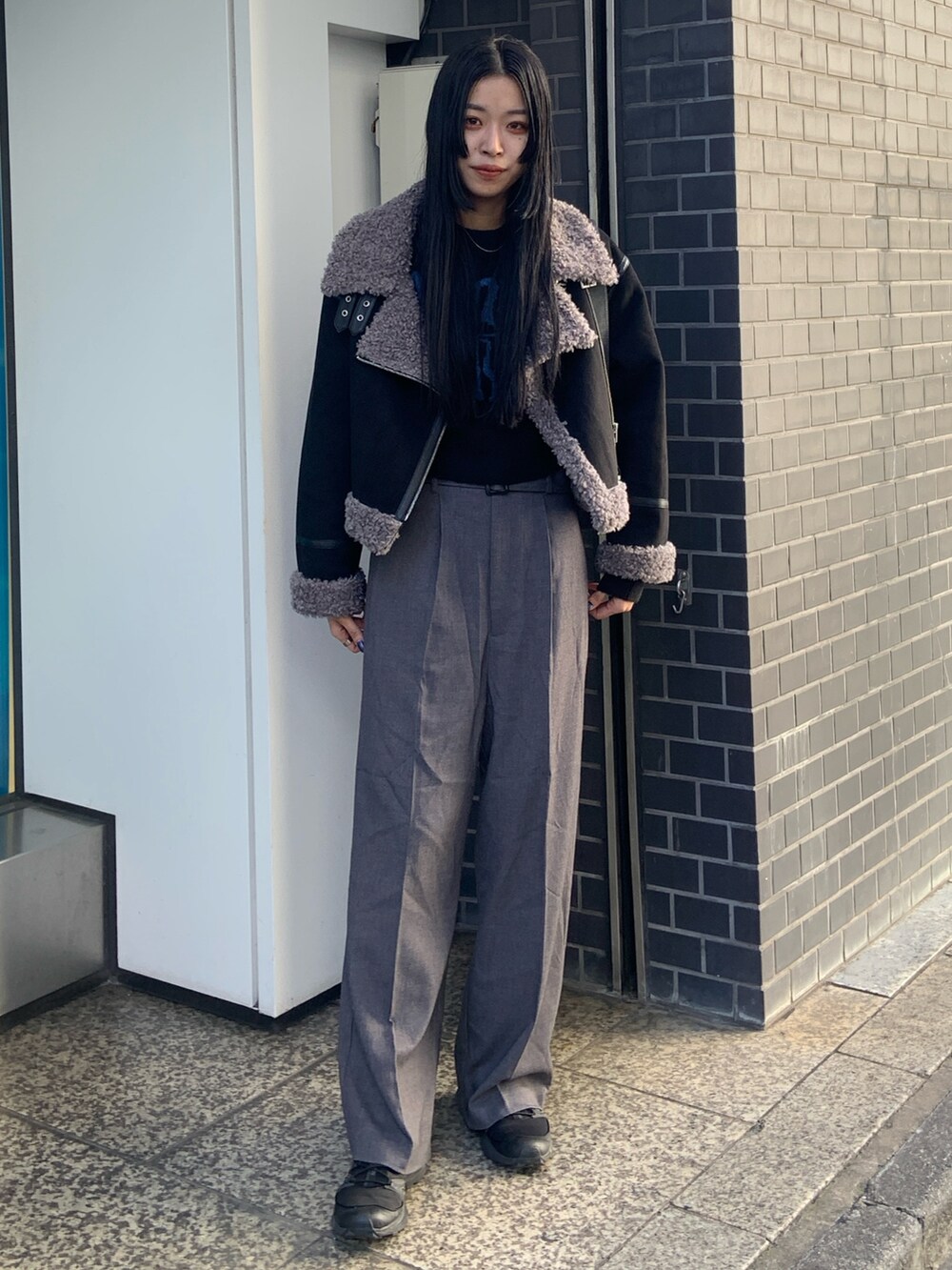 ブラック系のニット/セーター、グレー系のその他パンツ、ブラック系のムートンコートを着用したレディースの冬コーディネートの2枚目の写真