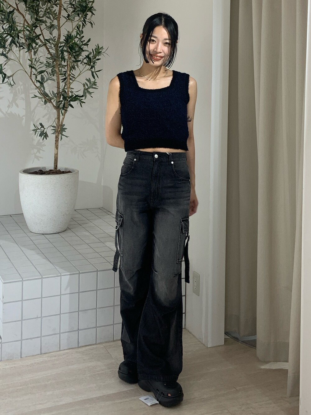 ブラック系のニット/セーター、ブラック系のデニムパンツ、ブラック系のサンダルを着用したレディースの夏コーディネートの2枚目の写真