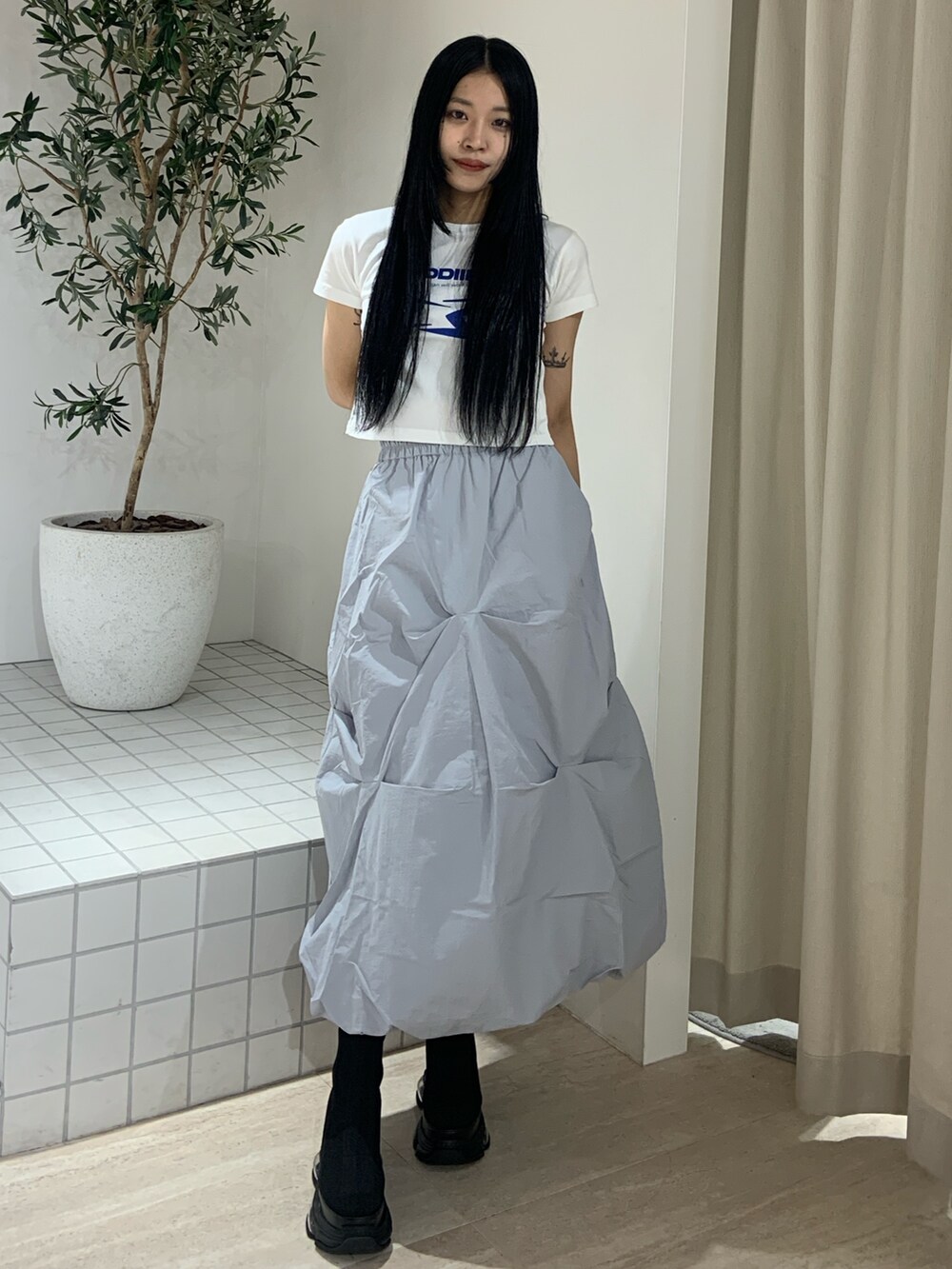 ホワイト系のTシャツ/カットソー、ブルー系のスカート、ブラック系のブーツを着用したレディースの春コーディネートの2枚目の写真