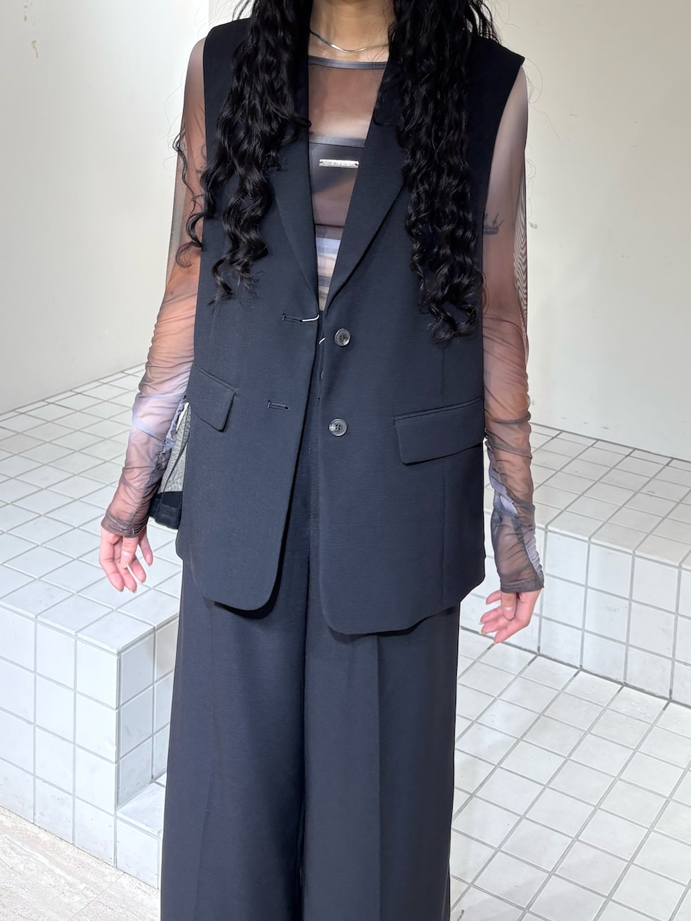 ブラック系のベスト、ブラック系のスラックス、ブラウン系のTシャツ/カットソーを着用したレディースの春コーディネートの4枚目の写真
