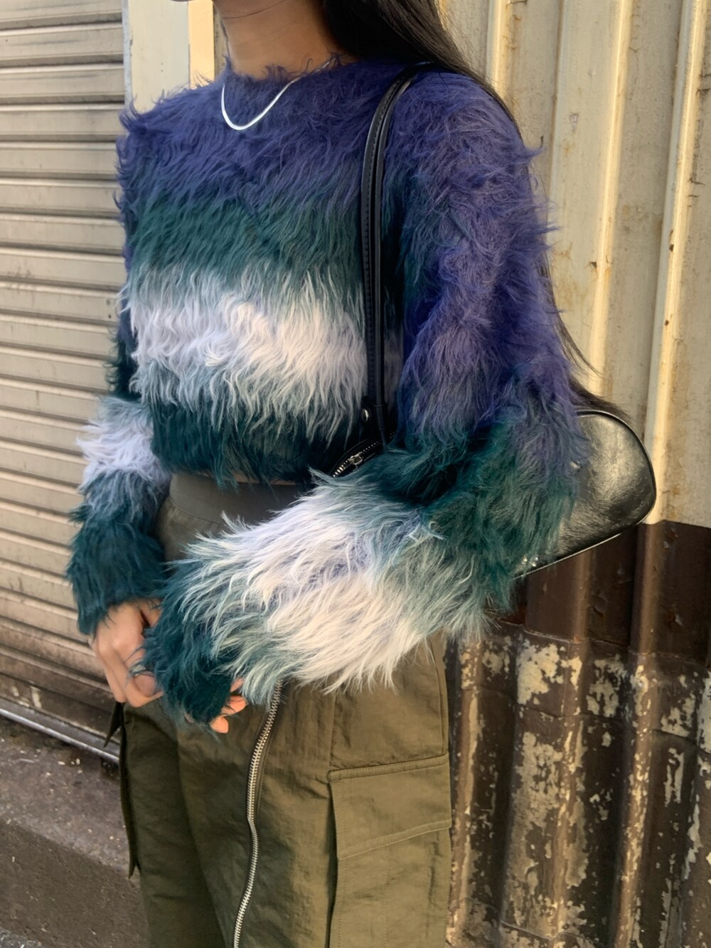 ブルー系のニット/セーター、ブラック系のボストンバッグ、グリーン系のスカートを着用したレディースの冬コーディネートの5枚目の写真