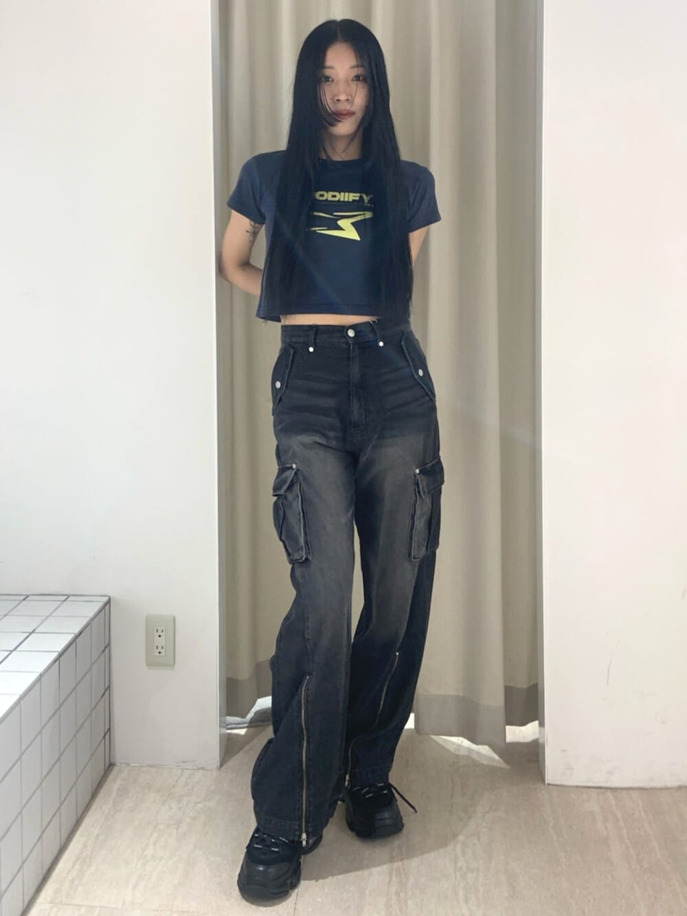 ブルー系のTシャツ/カットソー、ブラック系のデニムパンツ、ブラック系のスニーカーを着用したレディースの春コーディネートの2枚目の写真