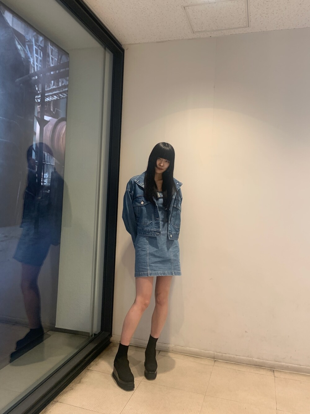 ブルー系のデニムジャケット、ブルー系のワンピース、ブラック系のブーツを着用したレディースの冬コーディネートの3枚目の写真