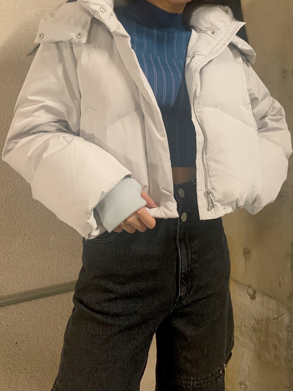 グレー系のダウンジャケット/コート、ブルー系のニット/セーター、ブラック系のデニムパンツを着用したレディースの秋コーディネートの4枚目の写真