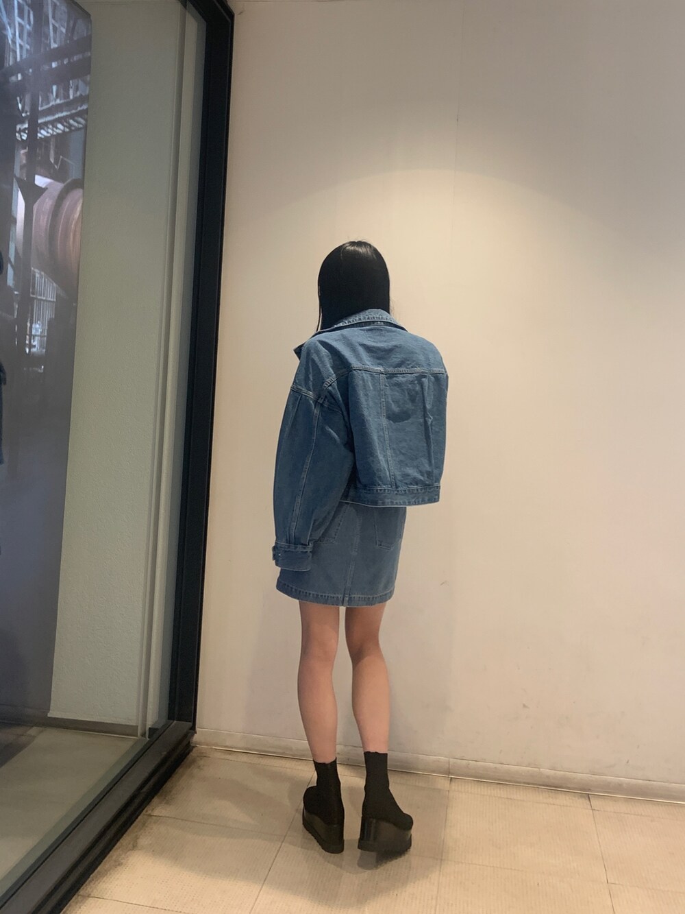 ブルー系のデニムジャケット、ブルー系のワンピース、ブラック系のブーツを着用したレディースの冬コーディネートの4枚目の写真