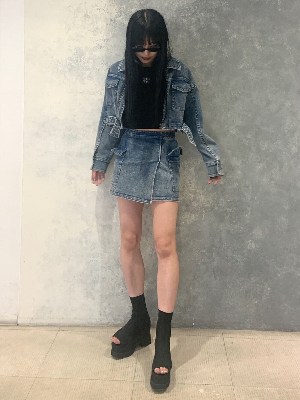 ブルー系のスカート、ブラック系のブーツ、ブルー系のデニムジャケットを着用したレディースの夏コーディネートの4枚目の写真