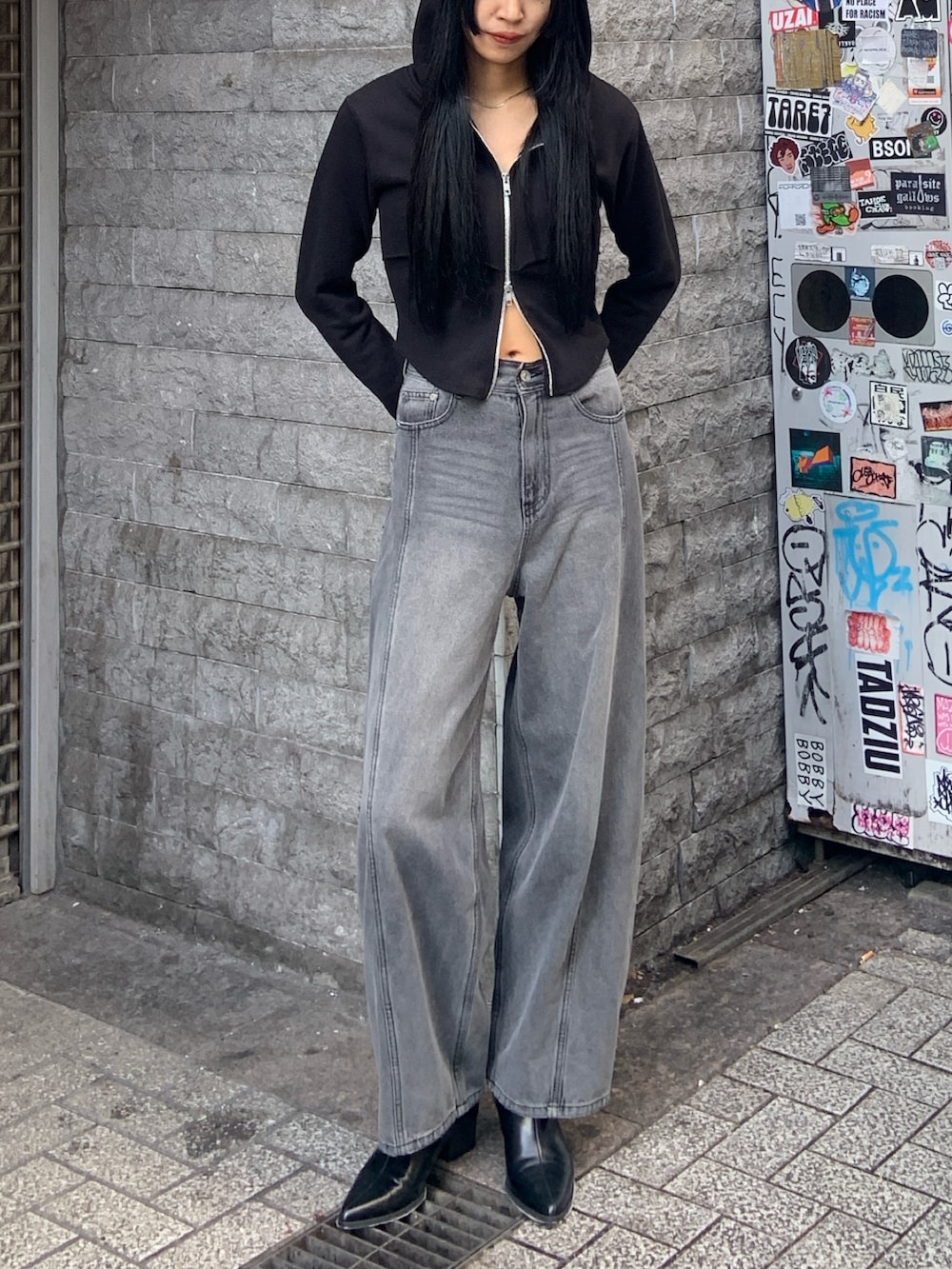 ブラック系のパーカー、ブラック系のデニムパンツ、ブラック系のブーツを着用したレディースの冬コーディネートの2枚目の写真