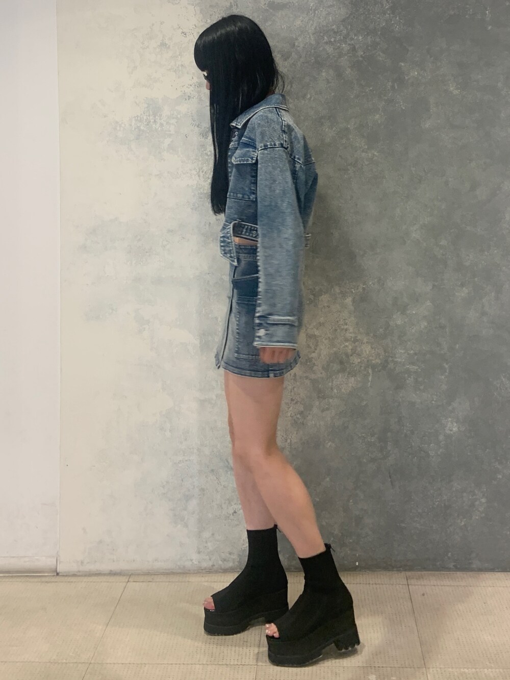 ブルー系のスカート、ブラック系のブーツ、ブルー系のデニムジャケットを着用したレディースの夏コーディネートの2枚目の写真