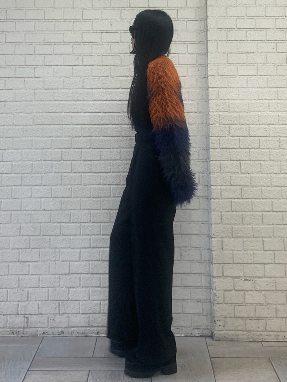 オレンジ系のニット/セーター、ブラック系のその他パンツ、ブラック系のブーツを着用したレディースの秋コーディネートの2枚目の写真