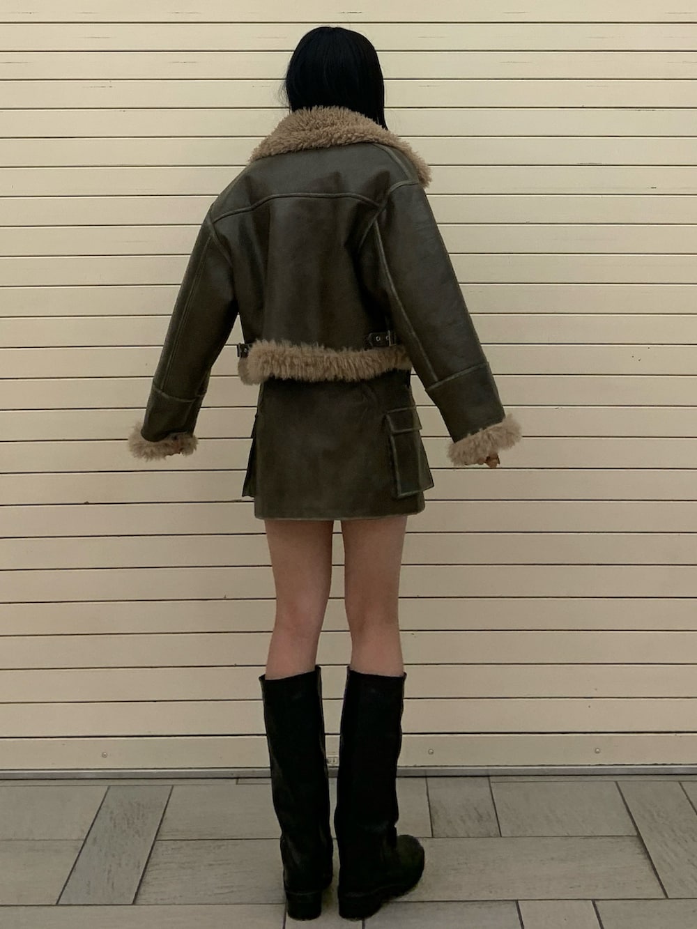 グリーン系のムートンコート、ブラック系のニット/セーター、グリーン系のスカートを着用したレディースの冬コーディネートの4枚目の写真