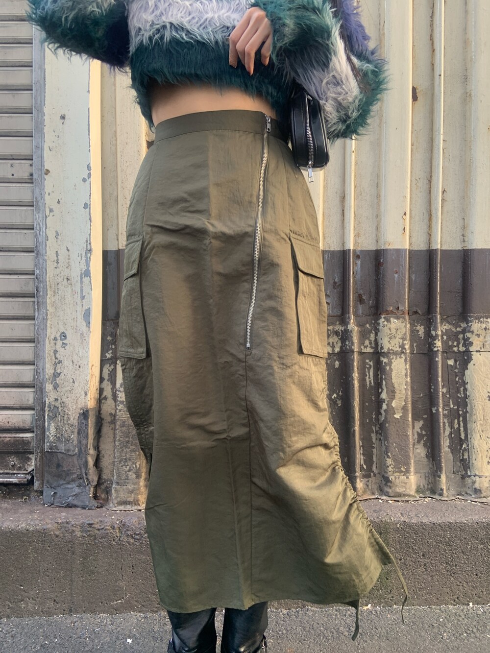 ブルー系のニット/セーター、ブラック系のボストンバッグ、グリーン系のスカートを着用したレディースの冬コーディネートの7枚目の写真