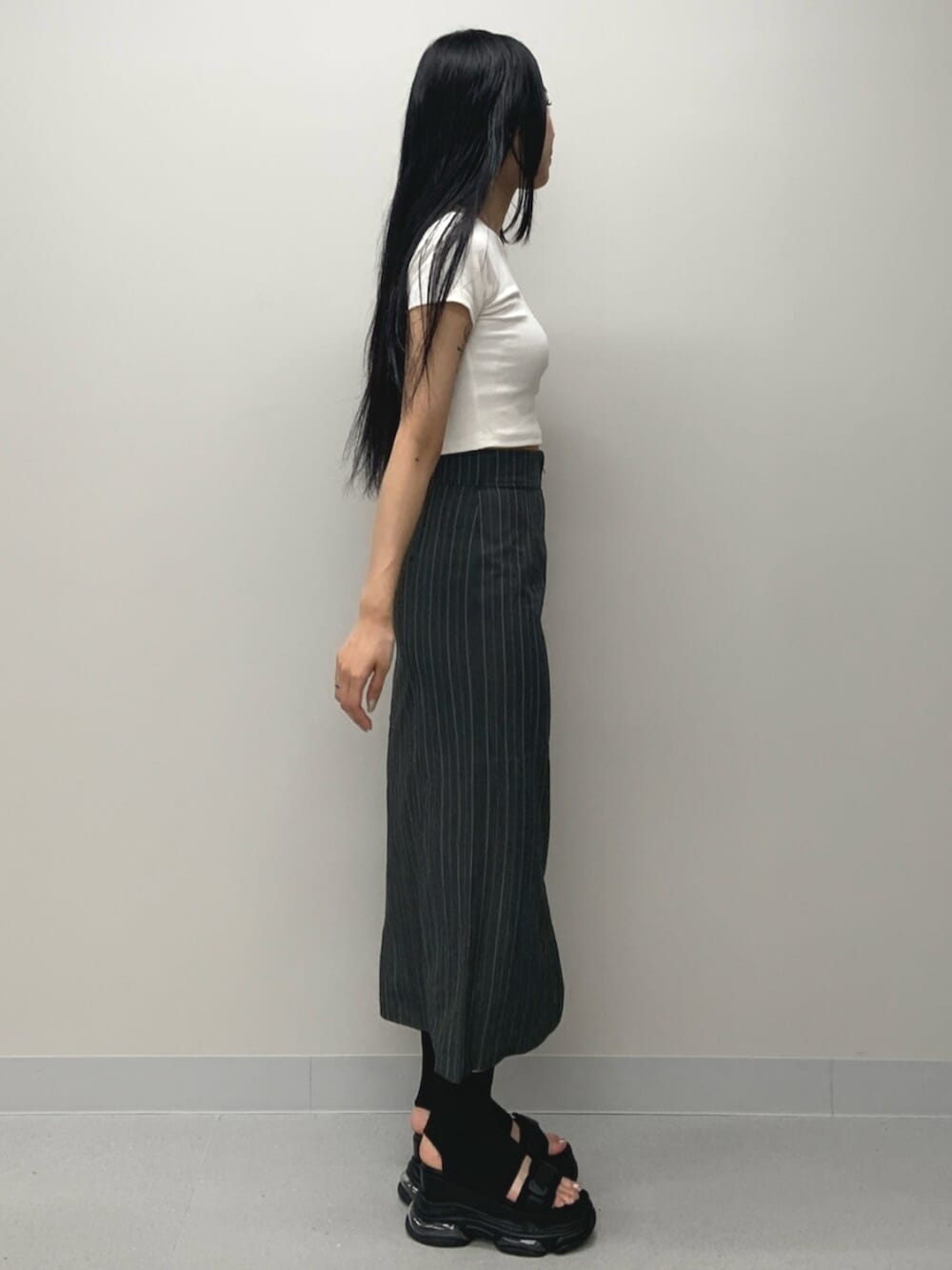 ブラック系のサンダル、ホワイト系のTシャツ/カットソー、グレー系のスカートを着用したレディースの春コーディネートの3枚目の写真