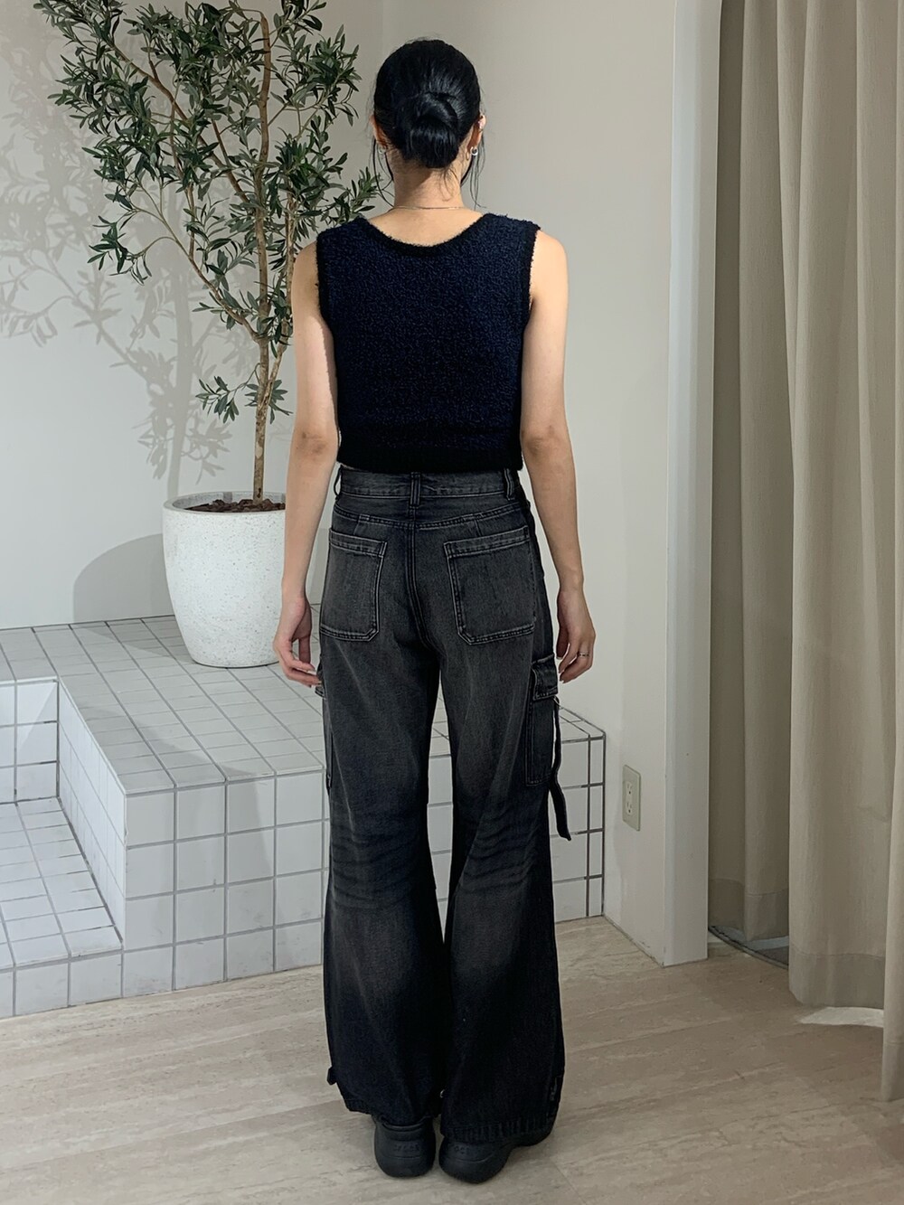 ブラック系のニット/セーター、ブラック系のデニムパンツ、ブラック系のサンダルを着用したレディースの夏コーディネートの4枚目の写真