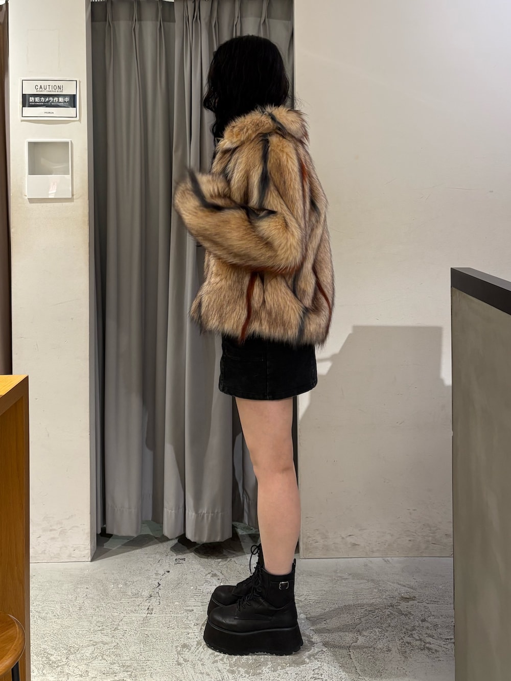 その他のステンカラーコート、ブラック系のスカート、ブラック系のブーツを着用したレディースの冬コーディネートの2枚目の写真