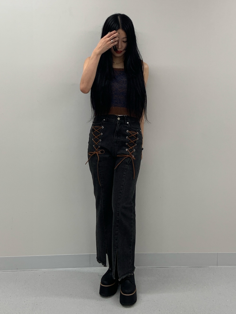 ブラック系のデニムパンツ、ブラック系のブーツ、ブラウン系のニット/セーターを着用したレディースの夏コーディネートの2枚目の写真
