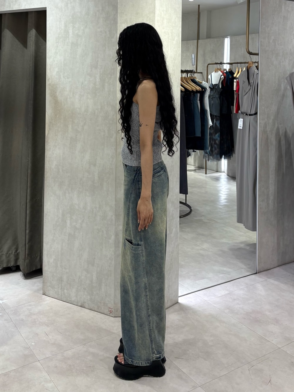 グレー系のタンクトップ、ブルー系のデニムパンツ、ブラック系のサンダルを着用したレディースの夏コーディネートの2枚目の写真