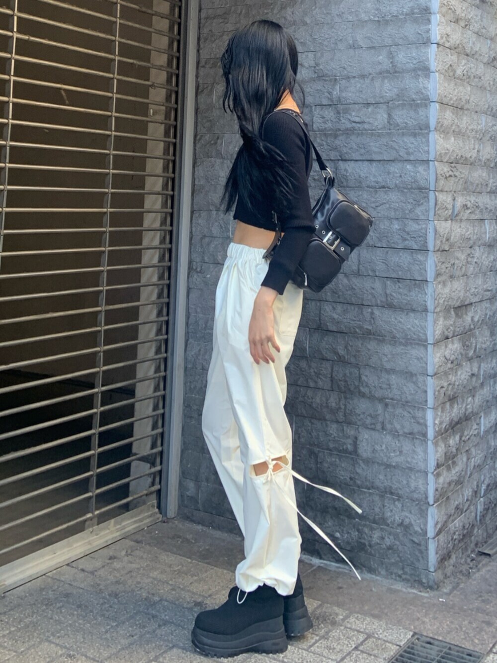 ブラック系のニット/セーター、ホワイト系のその他パンツ、ブラック系のブーツを着用したレディースの冬コーディネートの3枚目の写真