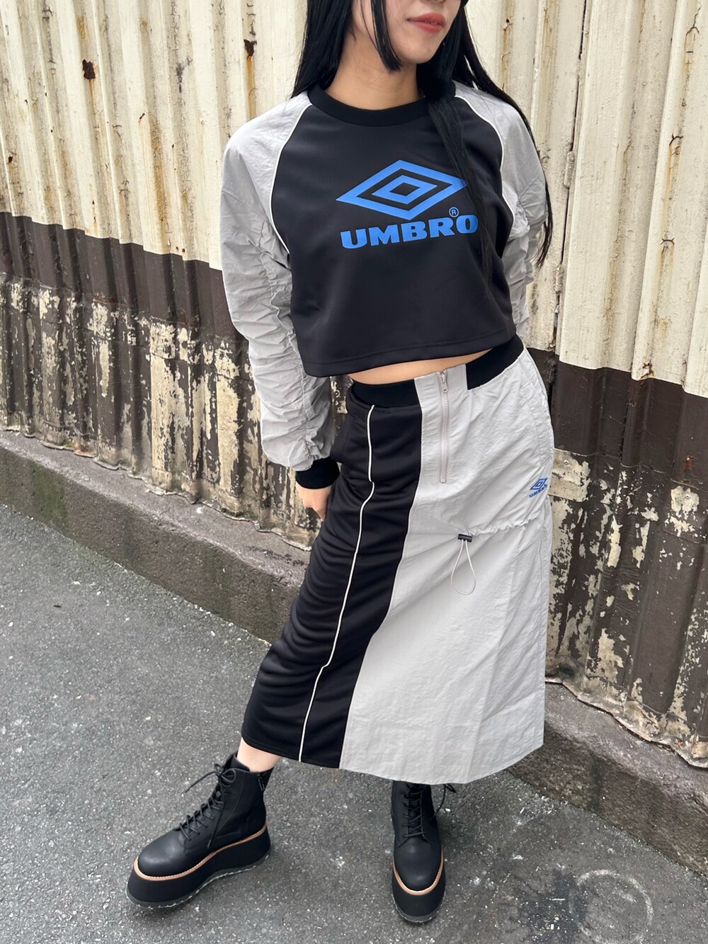 グレー系のTシャツ/カットソー、グレー系のスカート、ブラック系のブーツを着用したレディースの秋コーディネートの4枚目の写真