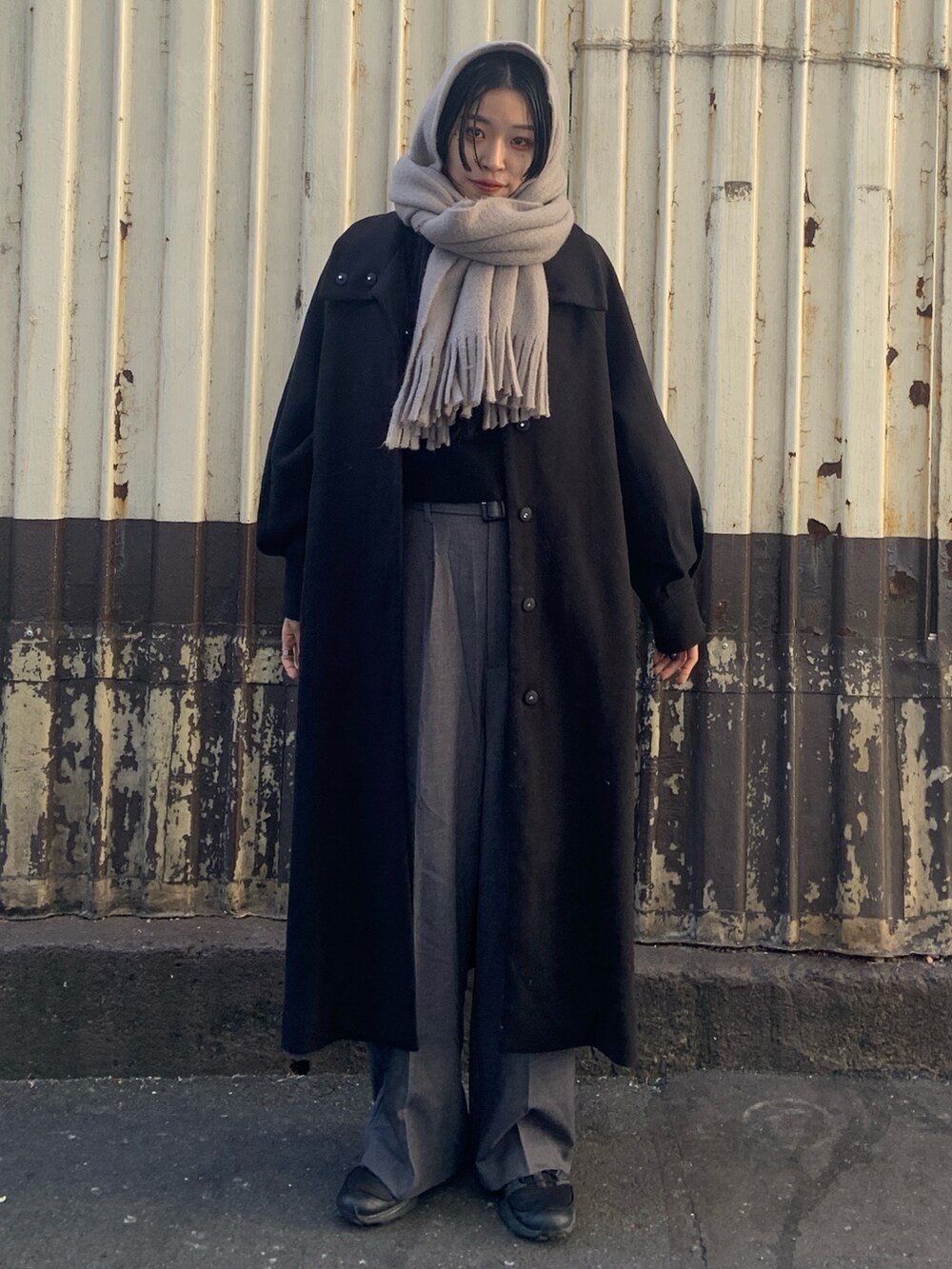 ブラック系のその他アウター、グレー系のその他パンツ、グレー系のマフラーを着用したレディースの冬コーディネートの2枚目の写真