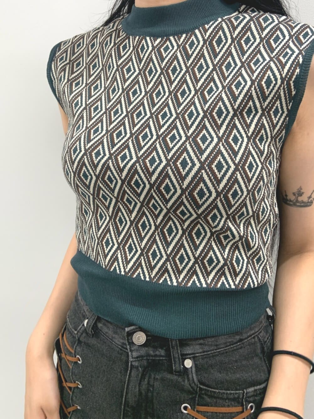 ブラック系のデニムパンツ、ブラック系のブーツ、グリーン系のタンクトップを着用したレディースの夏コーディネートの5枚目の写真