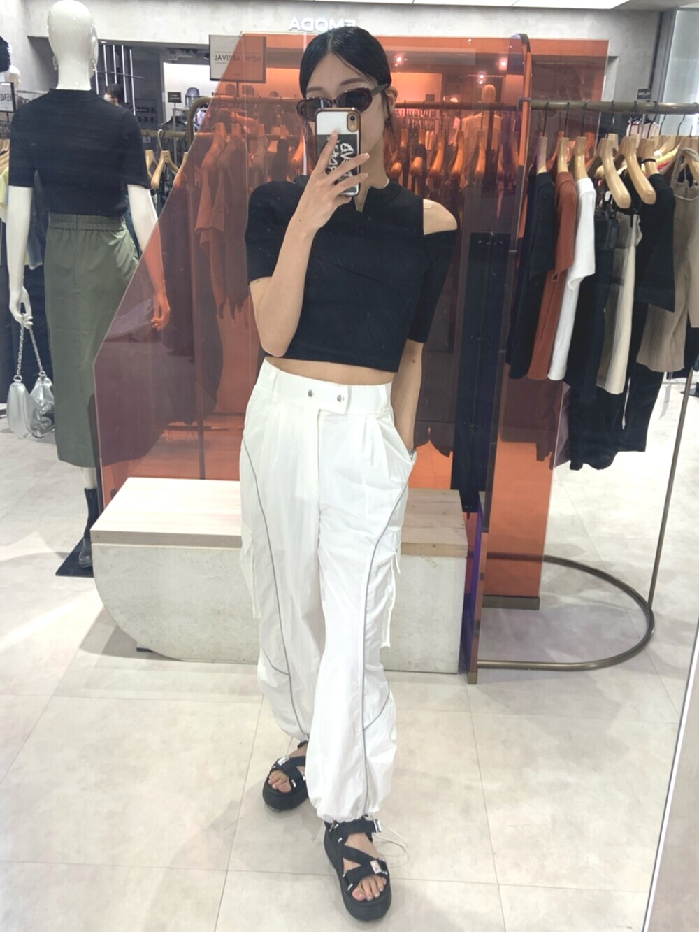 ブラック系のサンダル、ブラック系のニット/セーター、ホワイト系のカーゴパンツを着用したレディースの春コーディネートの2枚目の写真