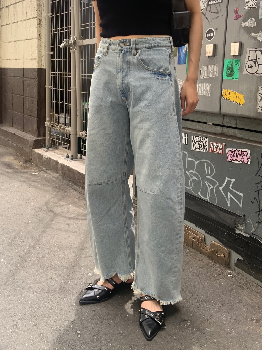 ブラック系のニット/セーター、ブルー系のデニムパンツ、ブラック系のパンプスを着用したレディースの夏コーディネートの4枚目の写真